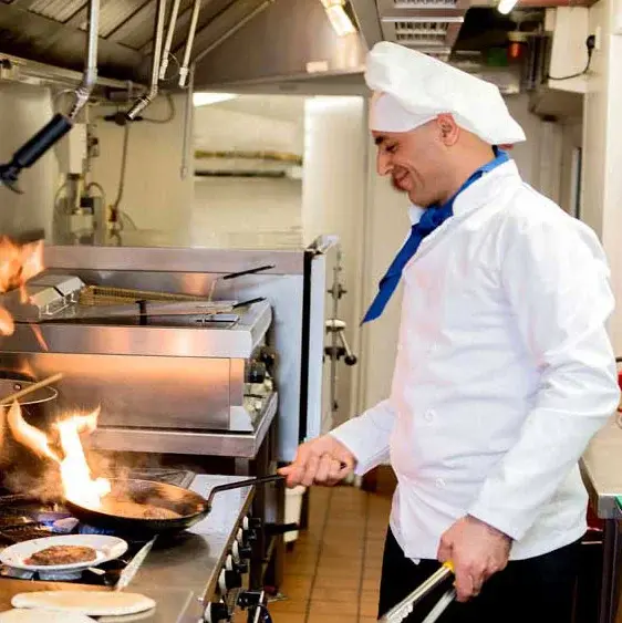 The Woods at Holly Tree Chef Created Meals, chef frying a dish.