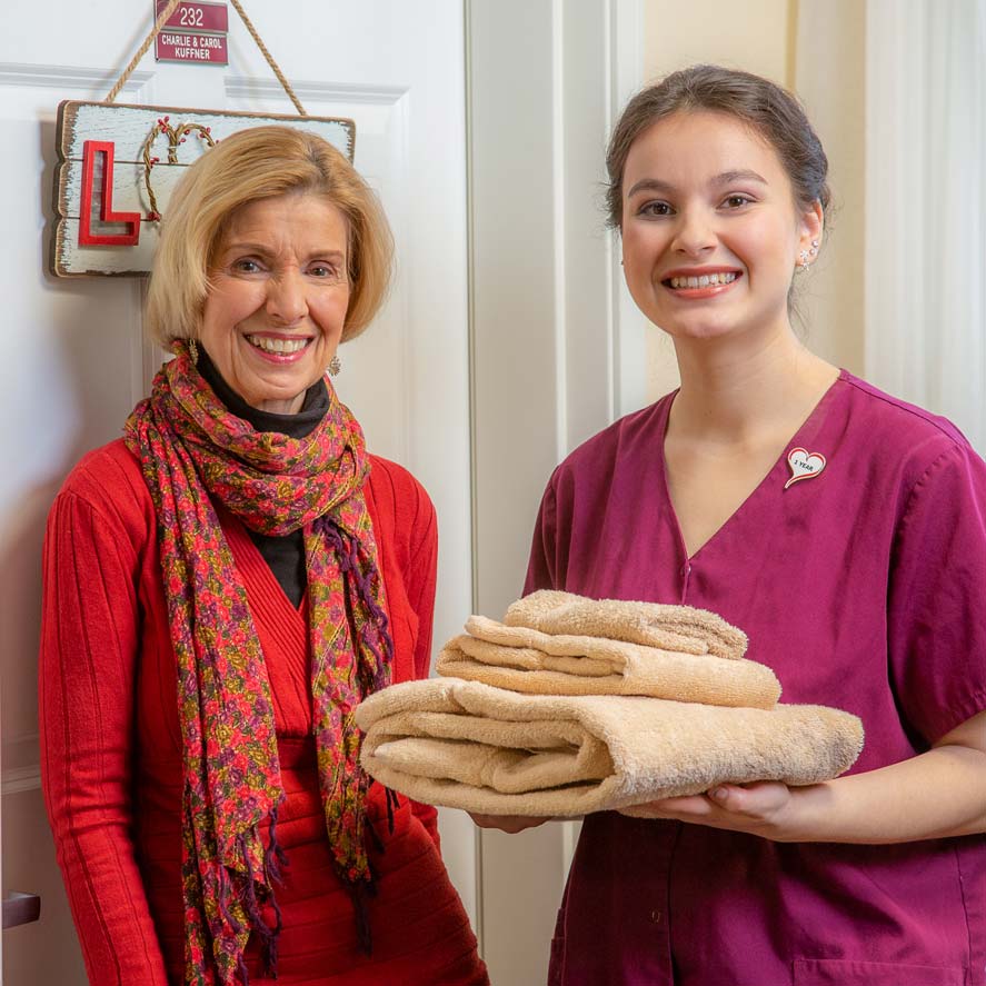 A team member delivering fresh linens to a resident at The Woods at Holly Tree